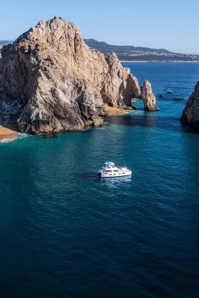 Rock arch catamaran at Swing into Success: Your 2026 Guide to Cabo San Lucas Junior Golf Programs on blue ocean, with cliffs