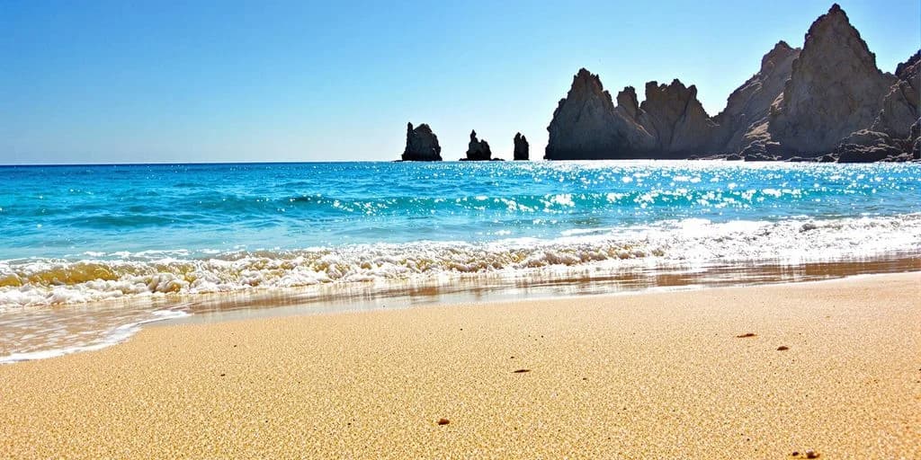 Sandy beach at Cabo Beach Locals Recommend: What You Need to Know waves on shore, rock formations