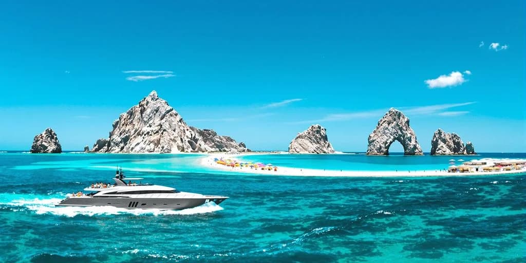 Luxury yacht at Cabo Excursions Ranked: What You Need to Know approaching beach, rock formations beyond