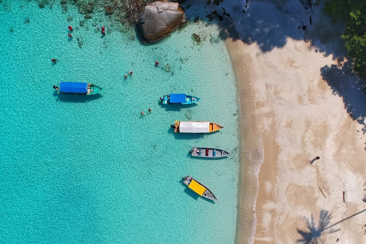 Beach aerial at Private Cabo Vacation Packages vs Group Tour Pricing with boats in clear water, swimmers