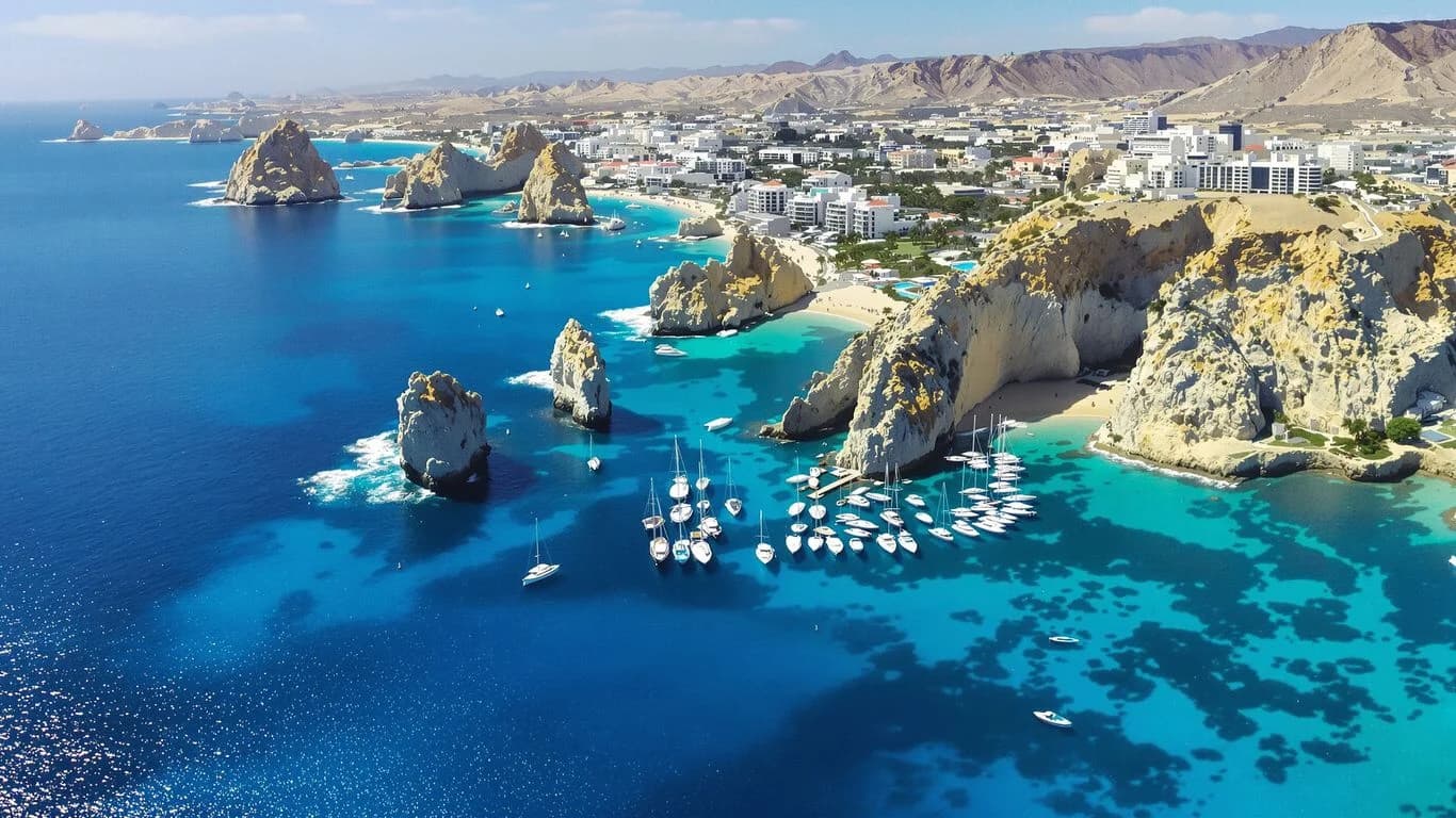 Coastal town aerial at Why Cabo Photographers Include Drone Shots at No Extra Cost with boats and rock formations