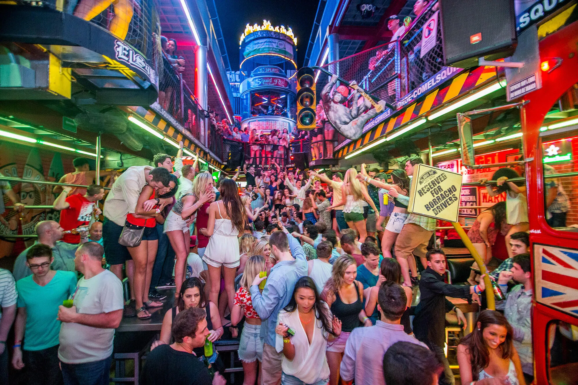 A crowd out on a neon-lit nightlife street in Cabo San Lucas