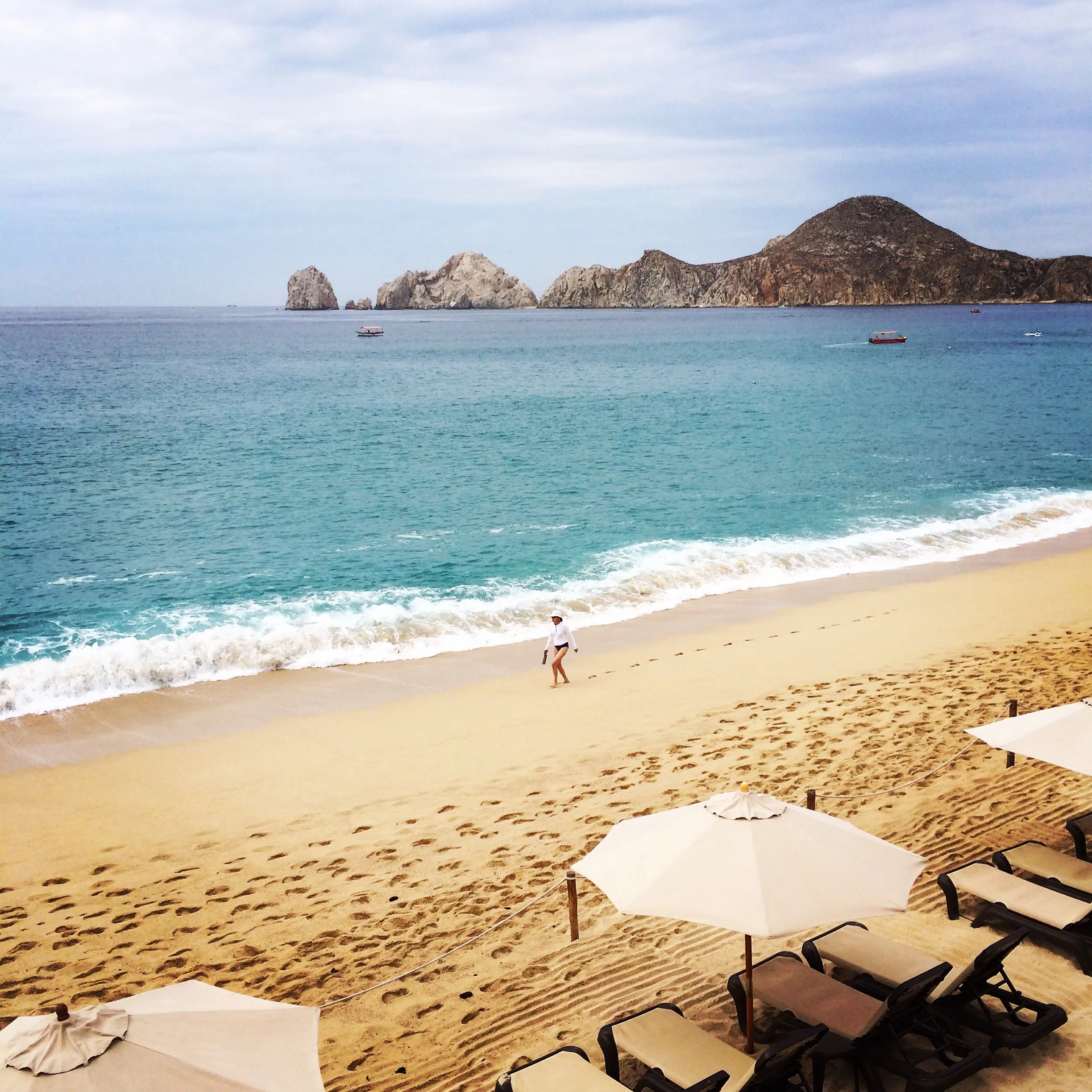 A sandy beach on the bay in Cabo San Lucas, Land's End in the distance
