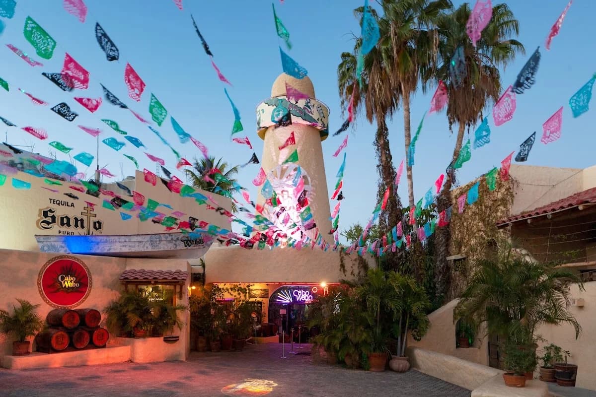 Building exterior at Cabo Wabo Cantina with colorful flags, neon sign in Cabo San Lucas