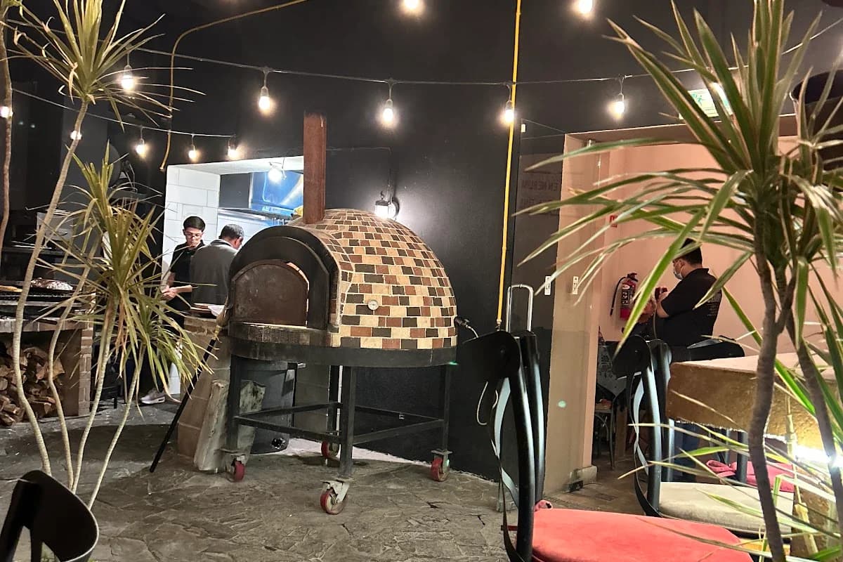 Pizza oven at Chamuyo on wheels, with string lights in Cabo San Lucas