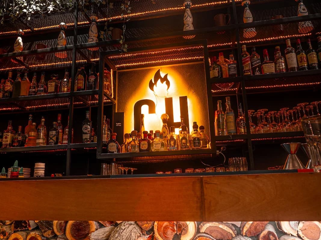 Bar shelf at Chamuyo Restaurant with liquor bottles, backlit logo in San José del Cabo