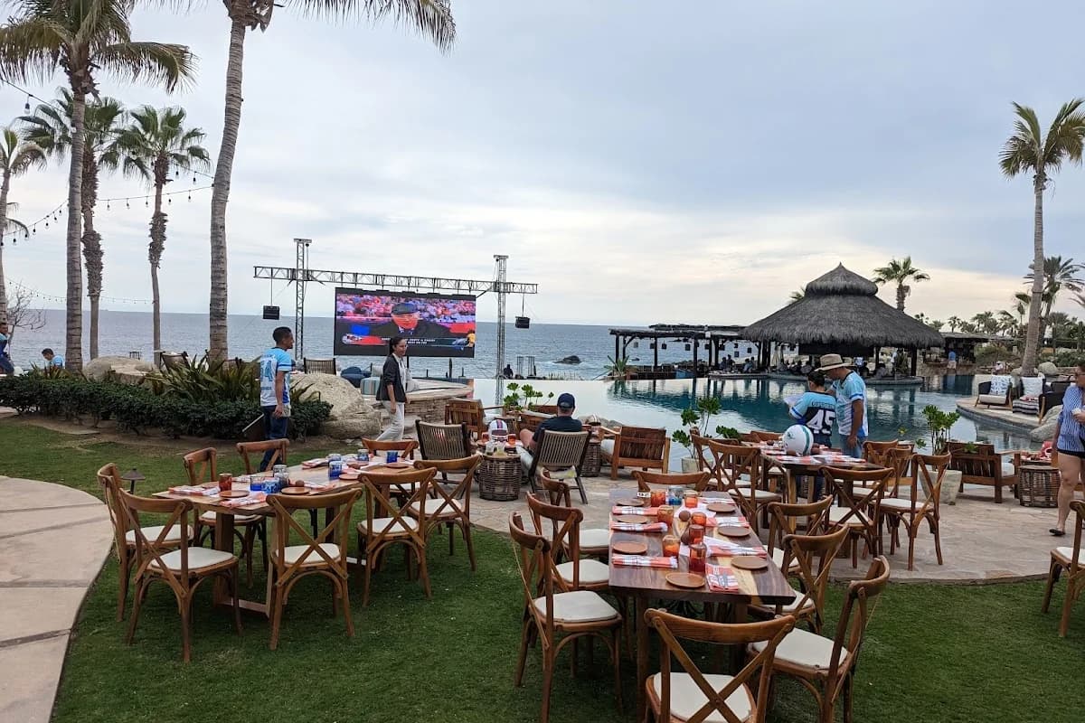 Outdoor restaurant at Cocina Del Mar by infinity-pool, with large screen in Cabo San Lucas