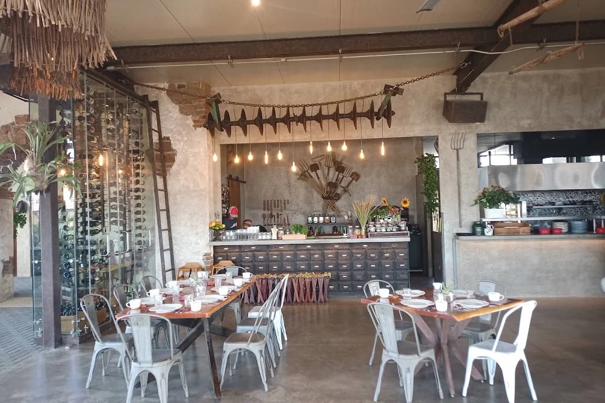 Restaurant interior at El Huerto Farm to Table with industrial decor, bar area in Cabo San Lucas