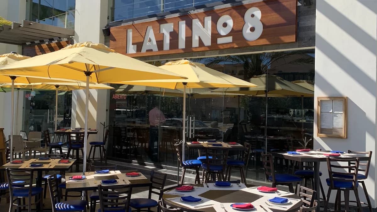 Restaurant exterior at Latino 8 with yellow umbrellas, glass facade in San José del Cabo