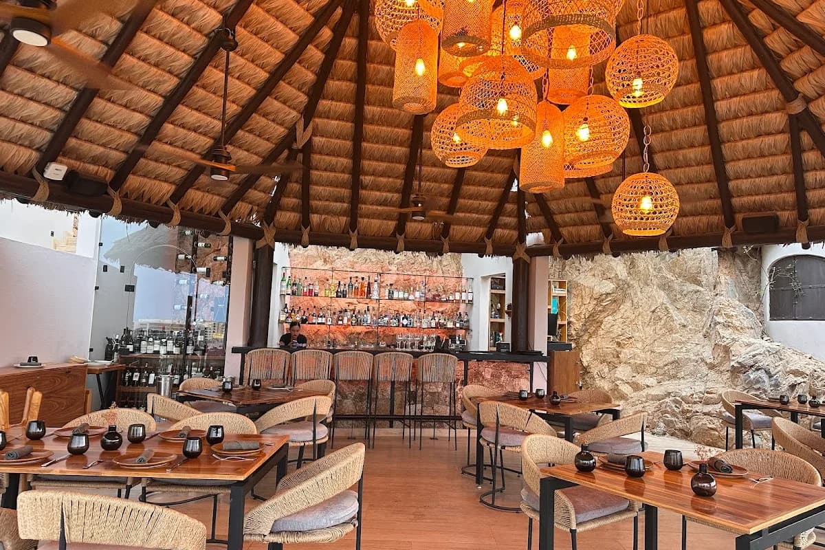 Bar area at Loretta Restaurant with thatched roof, woven lanterns in Cabo San Lucas