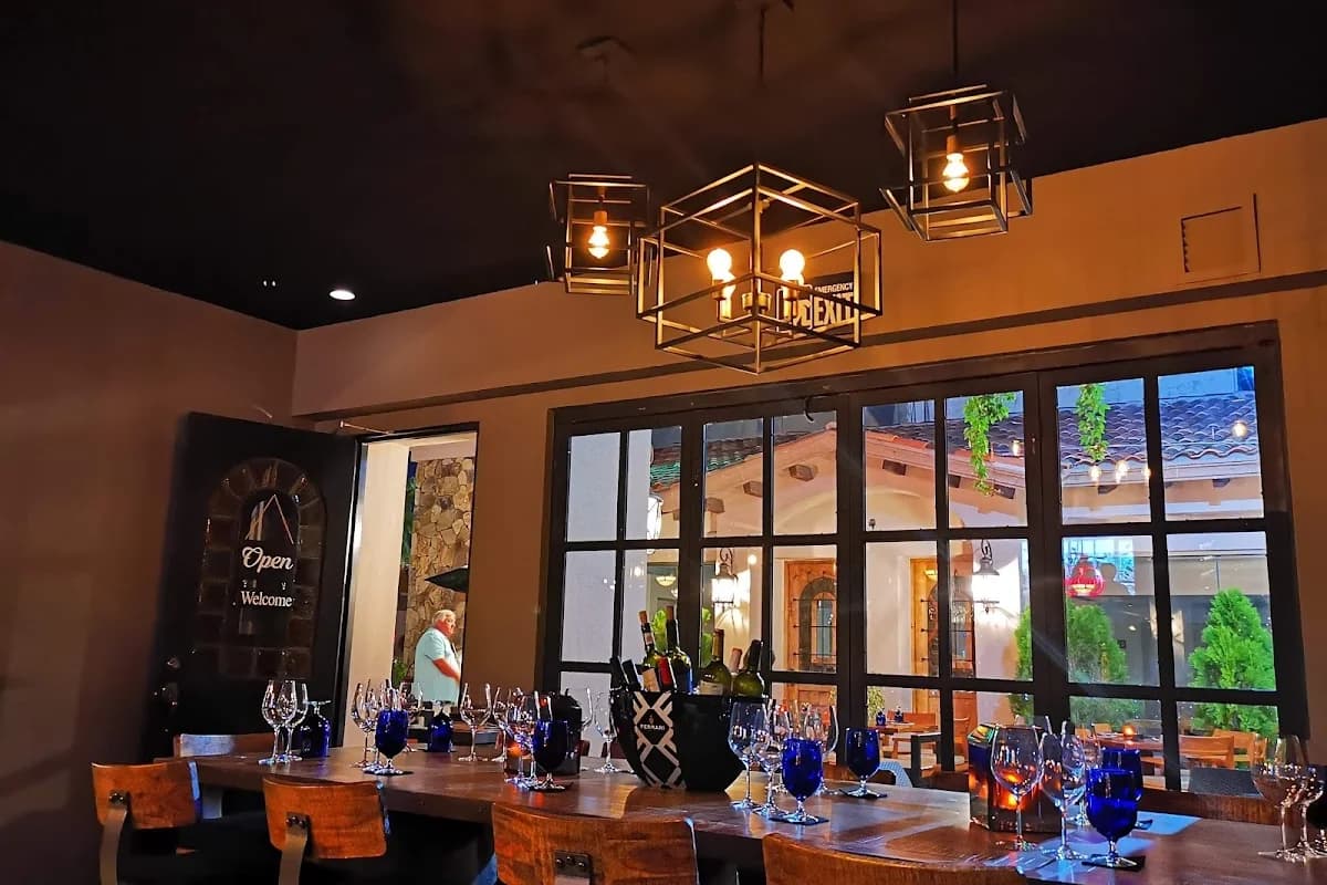 Restaurant interior at Romeo & Julieta wine bottles on table, modern lights in Cabo San Lucas