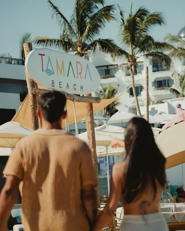 Beach sign at Tamara Beach with palm trees and building in San Lucas