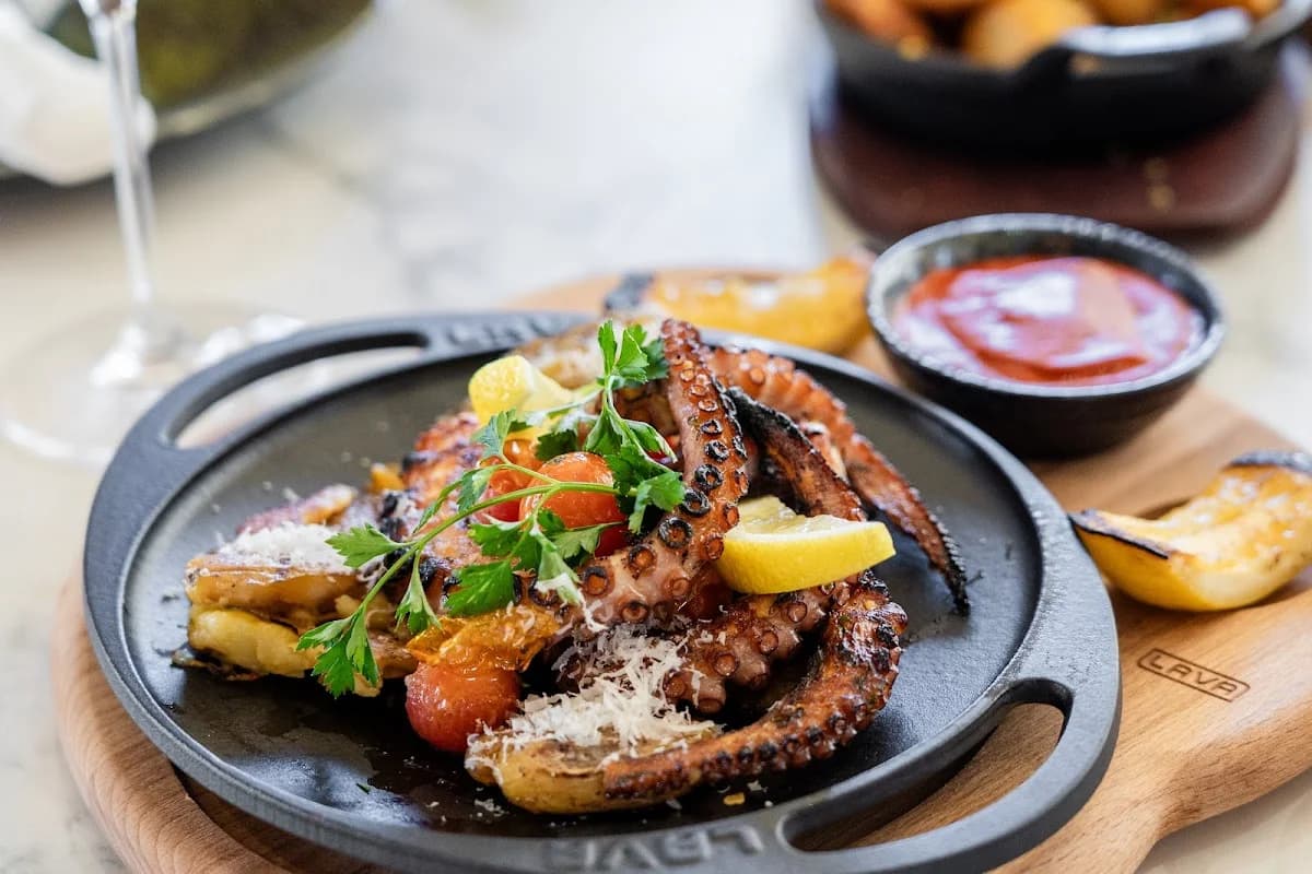 Plated octopus at The Woods Cabo with lemon and cherry tomatoes in Cabo San Lucas