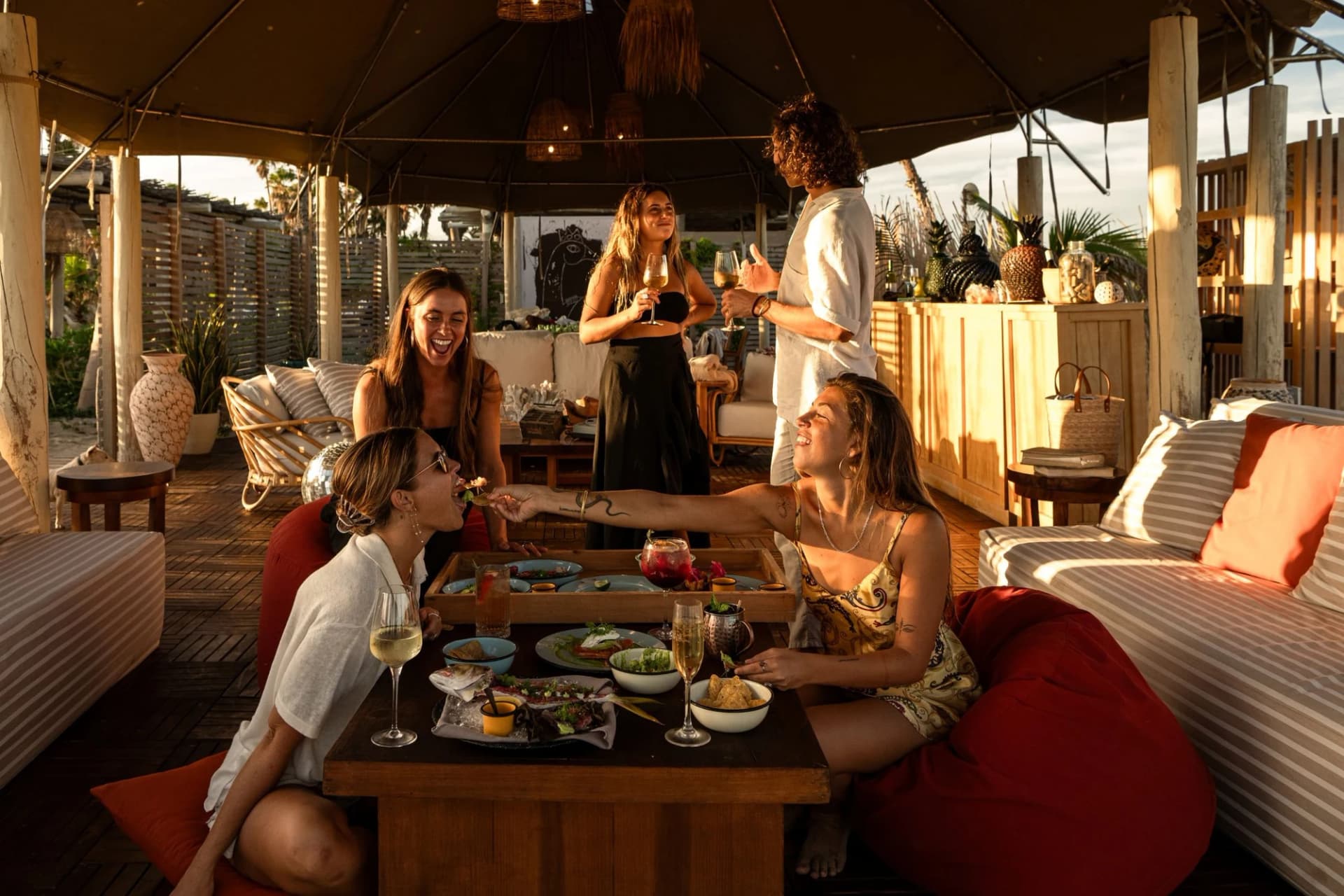 Outdoor party at Veleros Beach Club people holding drinks, at night in San José del Cabo