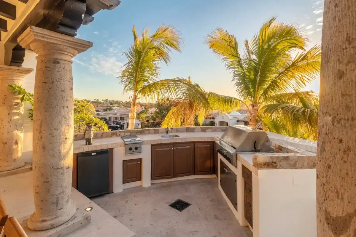 Outdoor kitchen at Casa Corona with grill, palm trees above in Cabo Del Sol