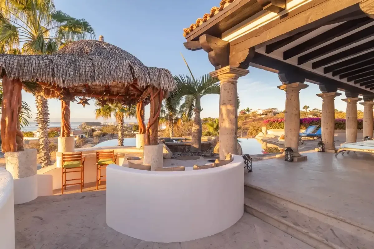 Outdoor seating area at Casa Corona with palapa, palm trees in Cabo Del Sol