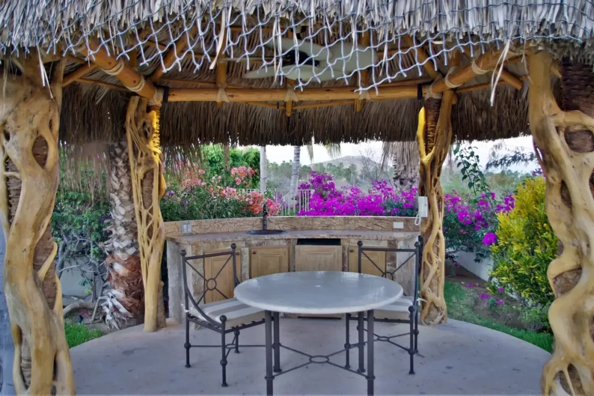 Outdoor kitchen at Casa Tortuga under palapa, with table in Cabo Del Sol