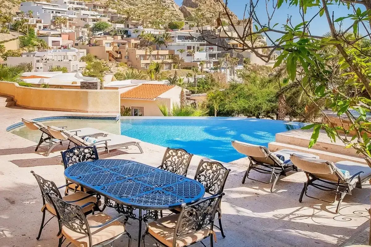 Outdoor dining table at Sunrise Villa with infinity pool, under blue sky in Pedregal Pacific