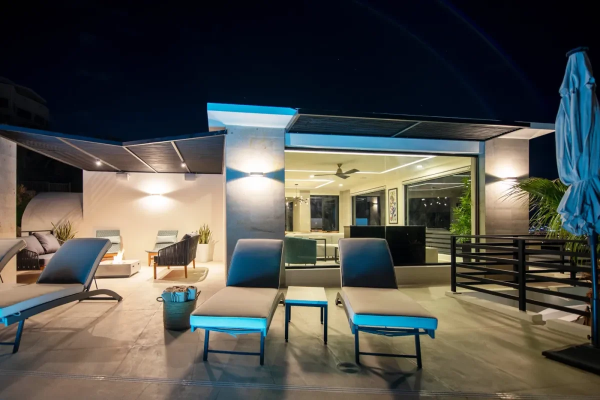 Lounge chairs at Villa De Lam at night, by building, lit in Pedregal Pacific