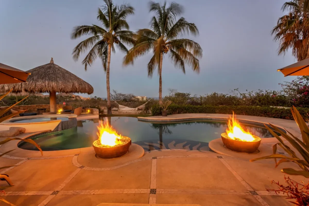 Pool fire pit at Villa Esquina at dusk, with palm trees in Cabo Del Sol