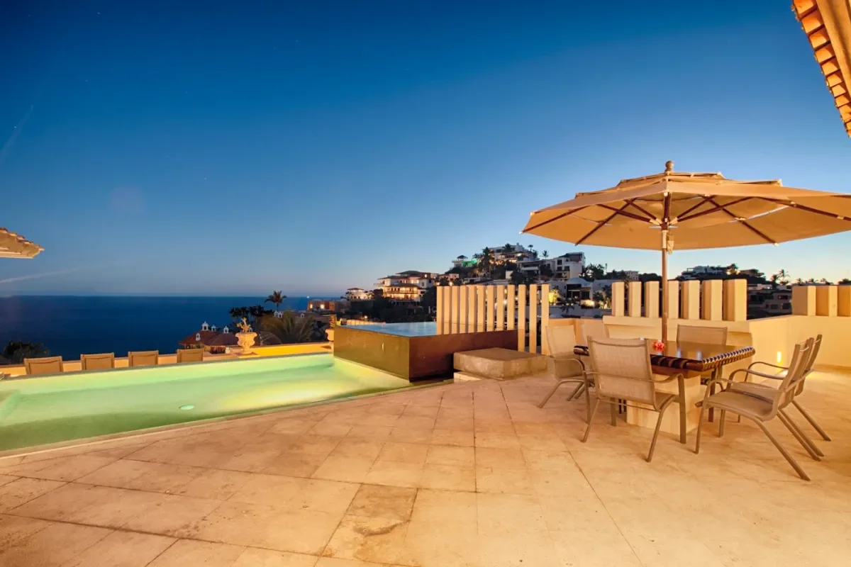 Outdoor terrace at Budget Sunset Cruise Cabo at dusk, with pool and ocean