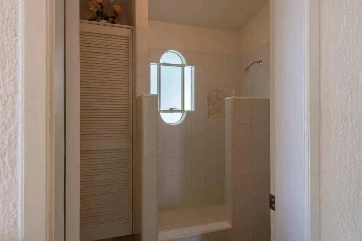 Shower at Villa Sun Guadalupe with oval window, white tiles