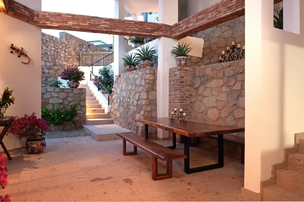 Outdoor dining area at Palmilla Beach Parking with stone wall, wooden table