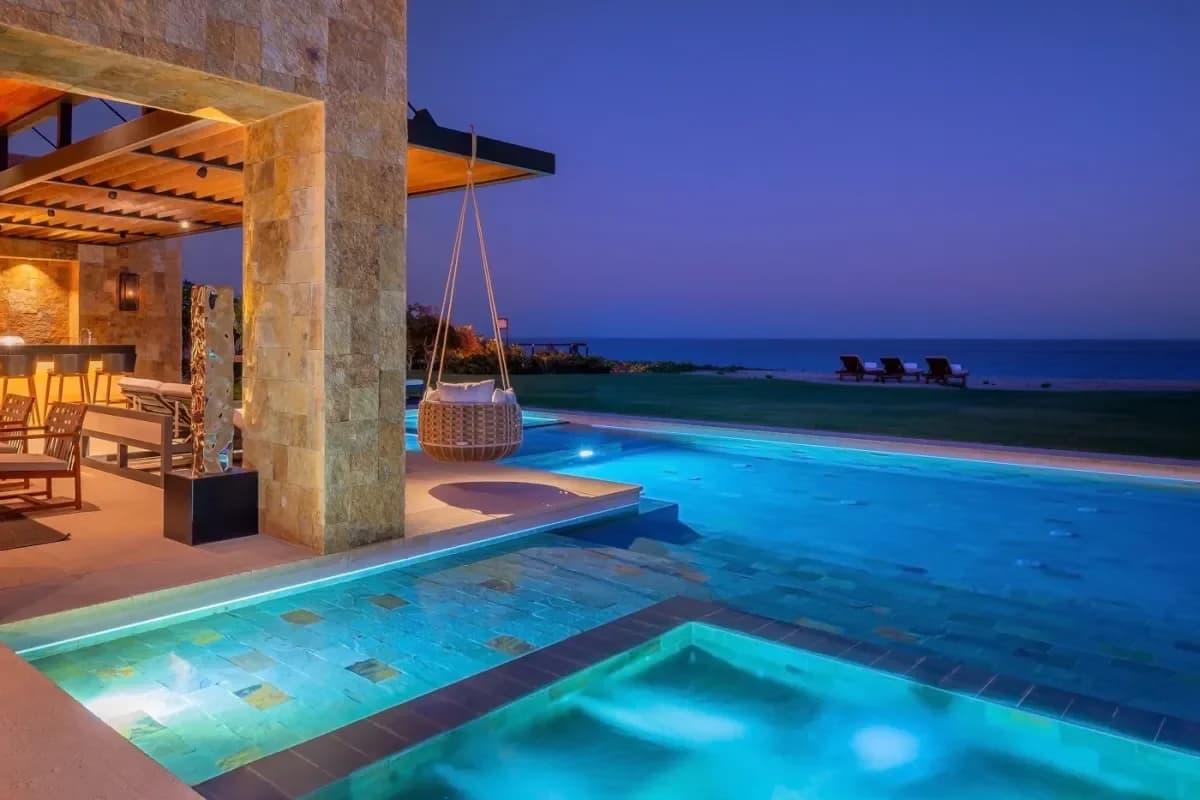 Outdoor pool at Cabo Villas vs. All-Inclusive Resorts: Your Local Expert Guide at night with hanging chair