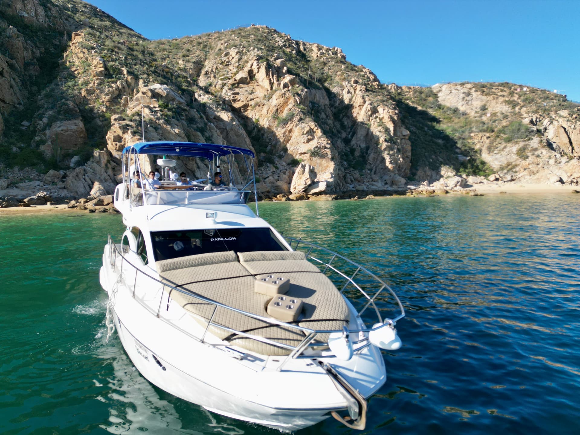 Boat bow on the Azimut 46ft with rocky coastline, green water in Cabo San Lucas