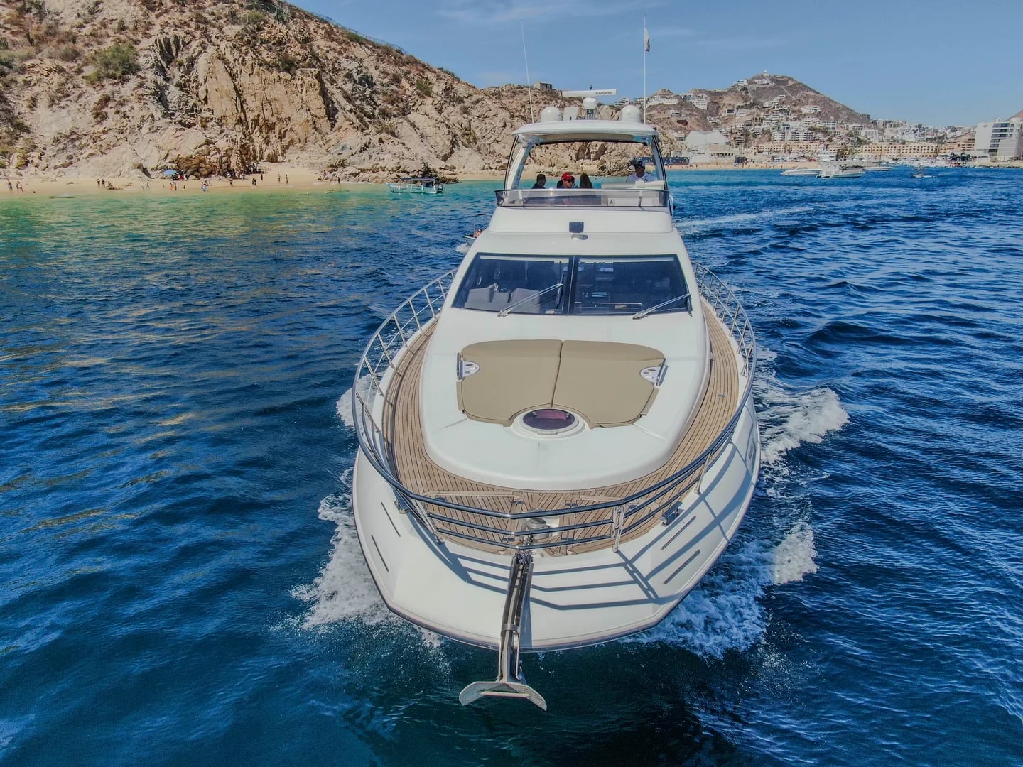 Yacht bow on the Azimut 68ft with people on flybridge, coastline in Cabo San Lucas