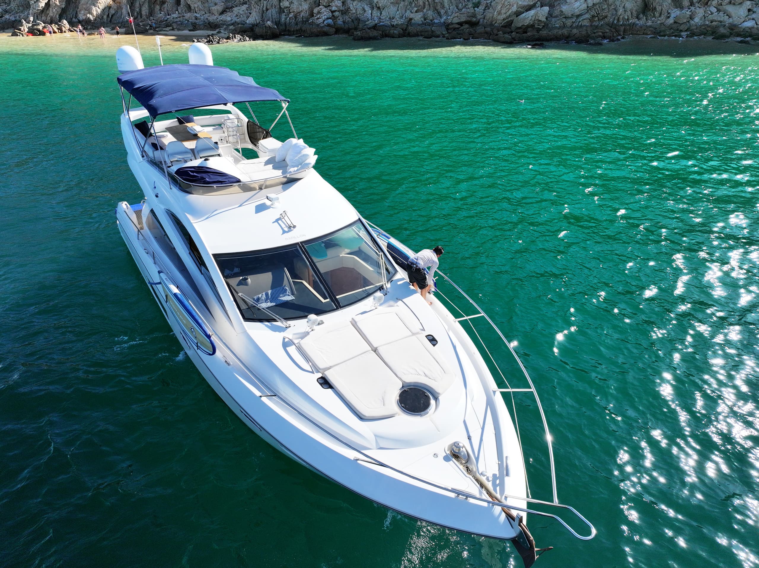 Boat deck at Best Yacht Charter Cabo San Lucas with rocky coastline, green water