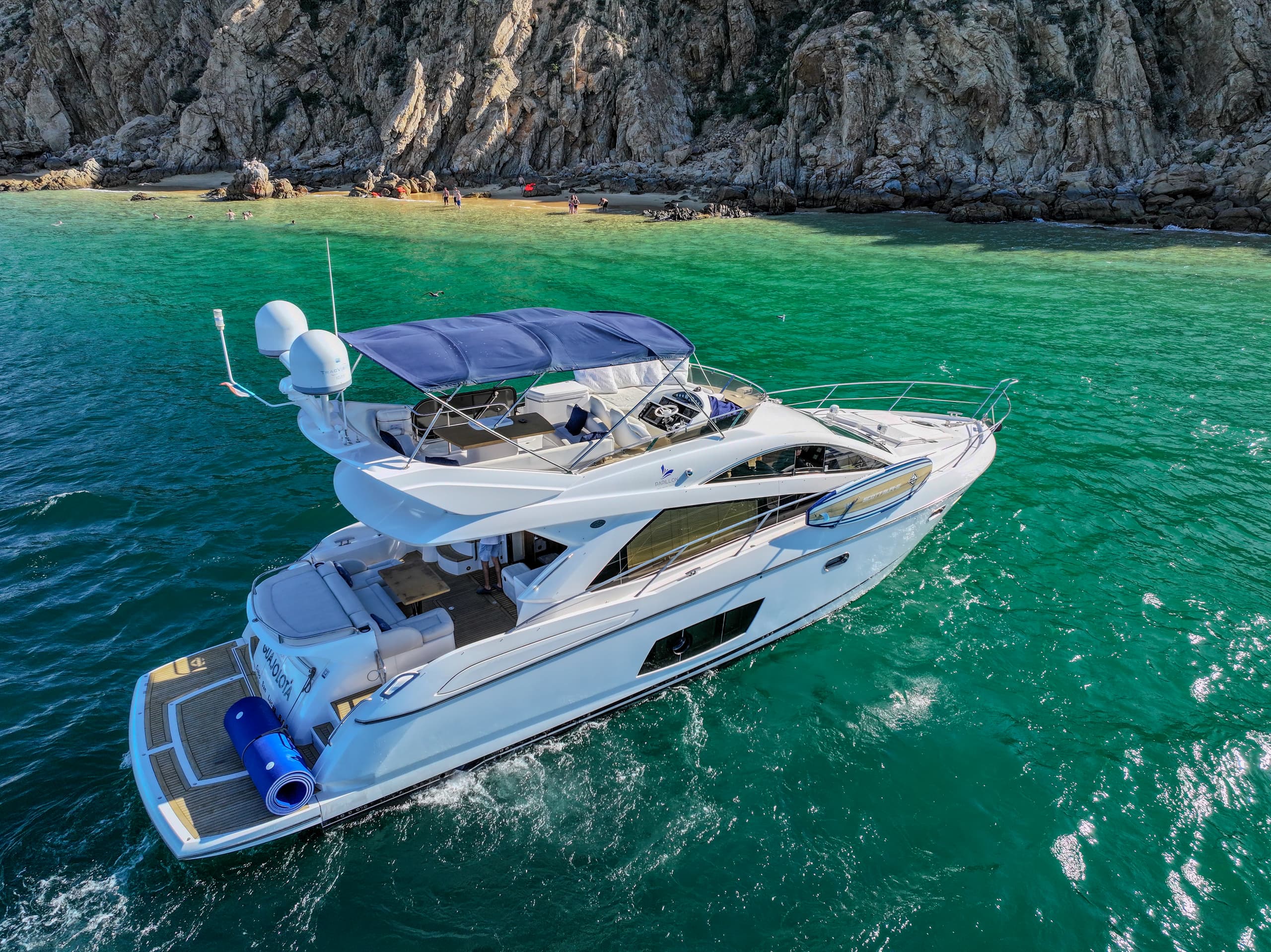 Luxury yacht aerial at Sunset Cruise Cabo For Families in clear green water, rocky coastline
